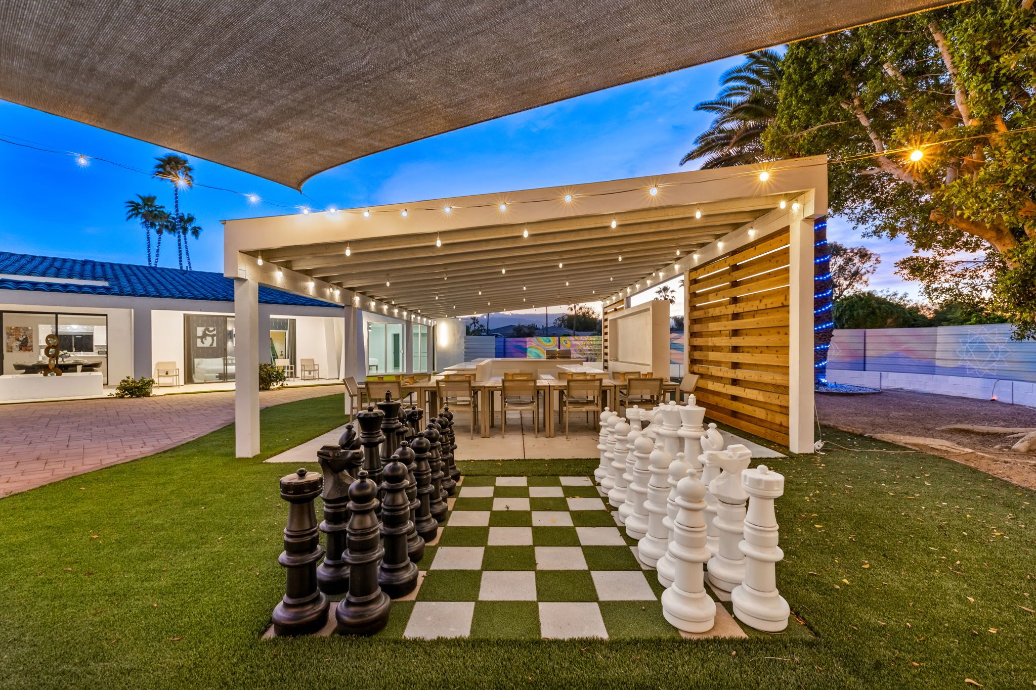 A chessboard set up on a lawn with a covered patio area in the background.