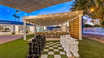 A chessboard set up on a lawn with a covered patio area in the background.