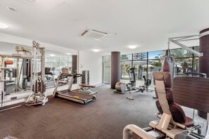 Et moderne fitnesscenter med forskellig træningsudstyr, en spejlvæg og store vinduer.