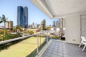 A balcony with a tennis court, city skyline, and modern buildings. - Fern Escape Resort Living near Beach and Nightlife (Gold Coast)