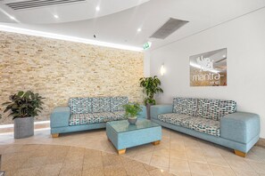 A reception area with two sofas, a coffee table, and a wall-mounted sign. - Fern Escape Resort Living near Beach and Nightlife (Gold Coast)
