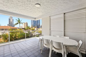 En balkon med et bord og stole, udsigt til bygninger og et flisegulv.