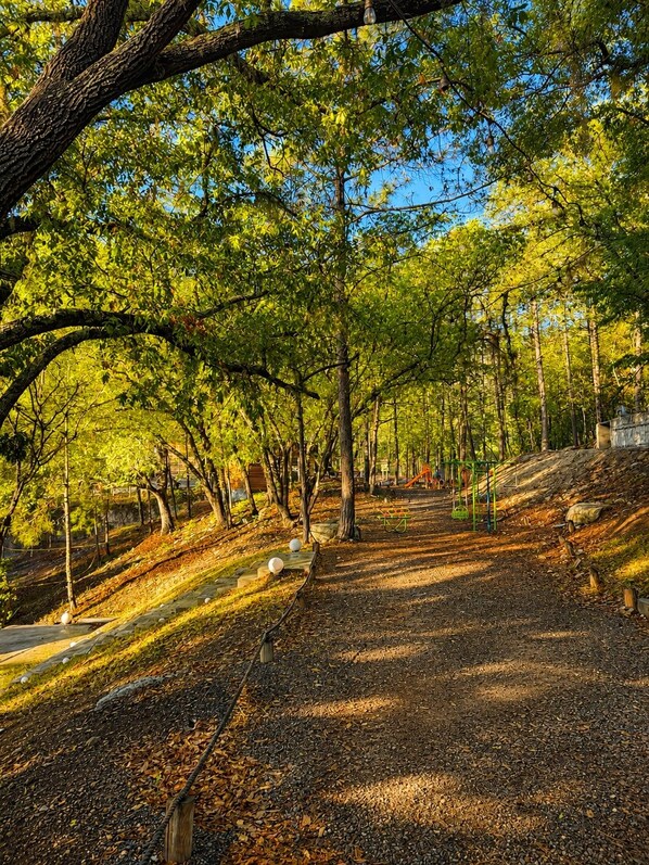 Ein Park mit gepflastertem Weg, Bänken und Spielgeräten.