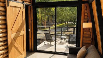 Une cabane en rondins moderne dotée d’une grande porte vitrée donnant sur un patio extérieur.
