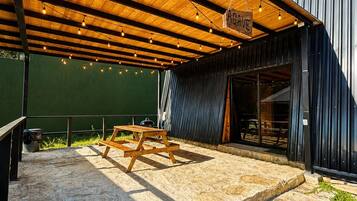 An outdoor patio with a wooden deck, a hanging sign, and a stone floor.