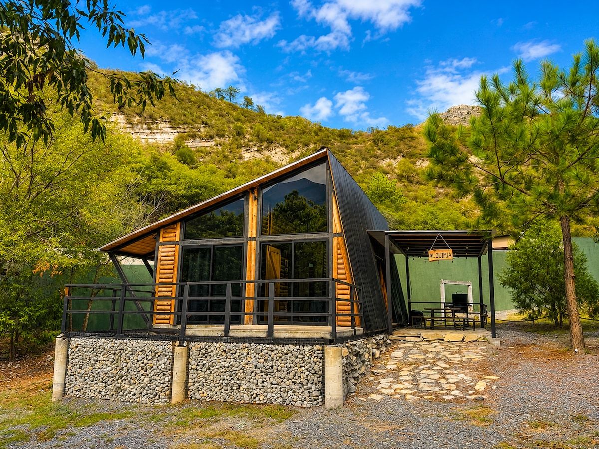 Una cabana amb fonaments de pedra, façana de fusta i grans finestres.