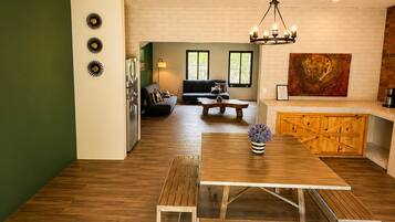 A modern living space with a dining area, a sofa, and a painting on the wall.