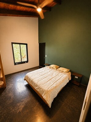 A bedroom with a bed, a window, a door, and a ceiling fan.