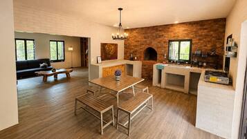 A modern kitchen with a brick wall, wooden flooring, a dining area with benches, and a built-in grill.