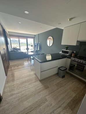 A modern kitchen with a black countertop, white cabinets, a microwave, and a stove. - El Encuentro. Espectacular para viaje y descanso. (Cancún)