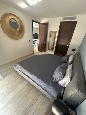 Ein Schlafzimmer mit einem großen Bett, einem runden Spiegel und einer Tür, die auf einen Balkon führt.