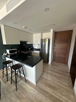 Une cuisine moderne dotée d’un îlot central, d’appareils électroménagers en acier inoxydable et d’une porte en bois.