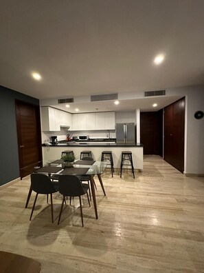 Une cuisine moderne avec des meubles blancs, un îlot central et un coin repas comprenant une table et des chaises.