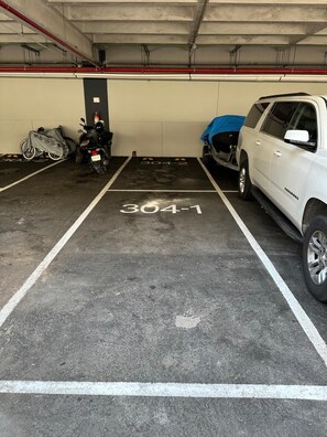 A parking garage with a white SUV parked in a marked space. - El Encuentro. Tu mejor opción para viajar. (Cancún)