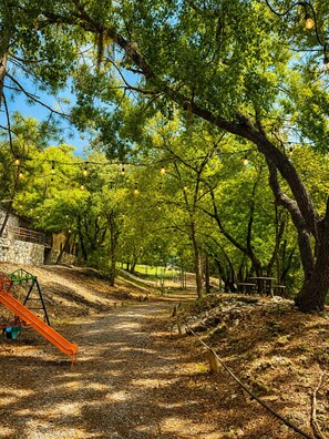 Ein Park mit einem Feldweg, Bäumen und einem Spielplatz mit einer Rutsche.