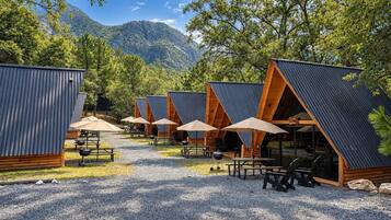 A row of A-frame cabins with outdoor seating and a gravel path.