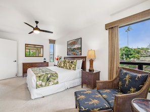 A bedroom with a bed, a nightstand, a chair, a ceiling fan, and a window with a view. - Wailea Ekahi Village 17D (Wailea)