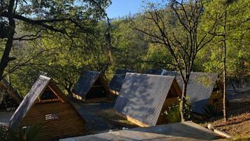 Ein Campingplatz mit mehreren Holzhütten, von denen einige Blechdächer haben, umgeben von Bäumen und natürlicher Landschaft.