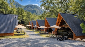 Une rangée de chalets en forme de «
A
» dotés d’un espace extérieur avec des sièges et bordée d’un chemin de gravier.