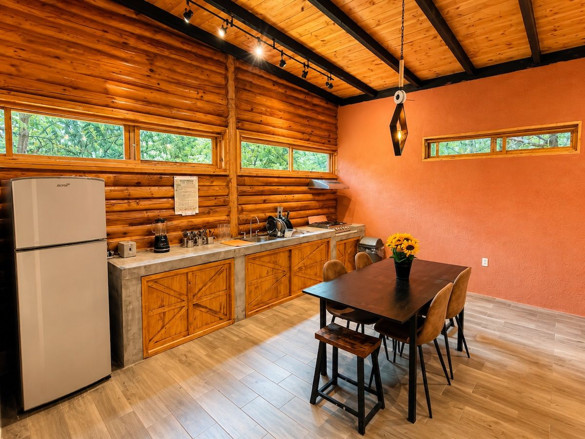 A kitchen with wooden cabinets, a refrigerator, and a dining table with chairs.
