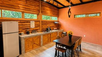 A kitchen with wooden cabinets, a refrigerator, and a dining table with chairs.