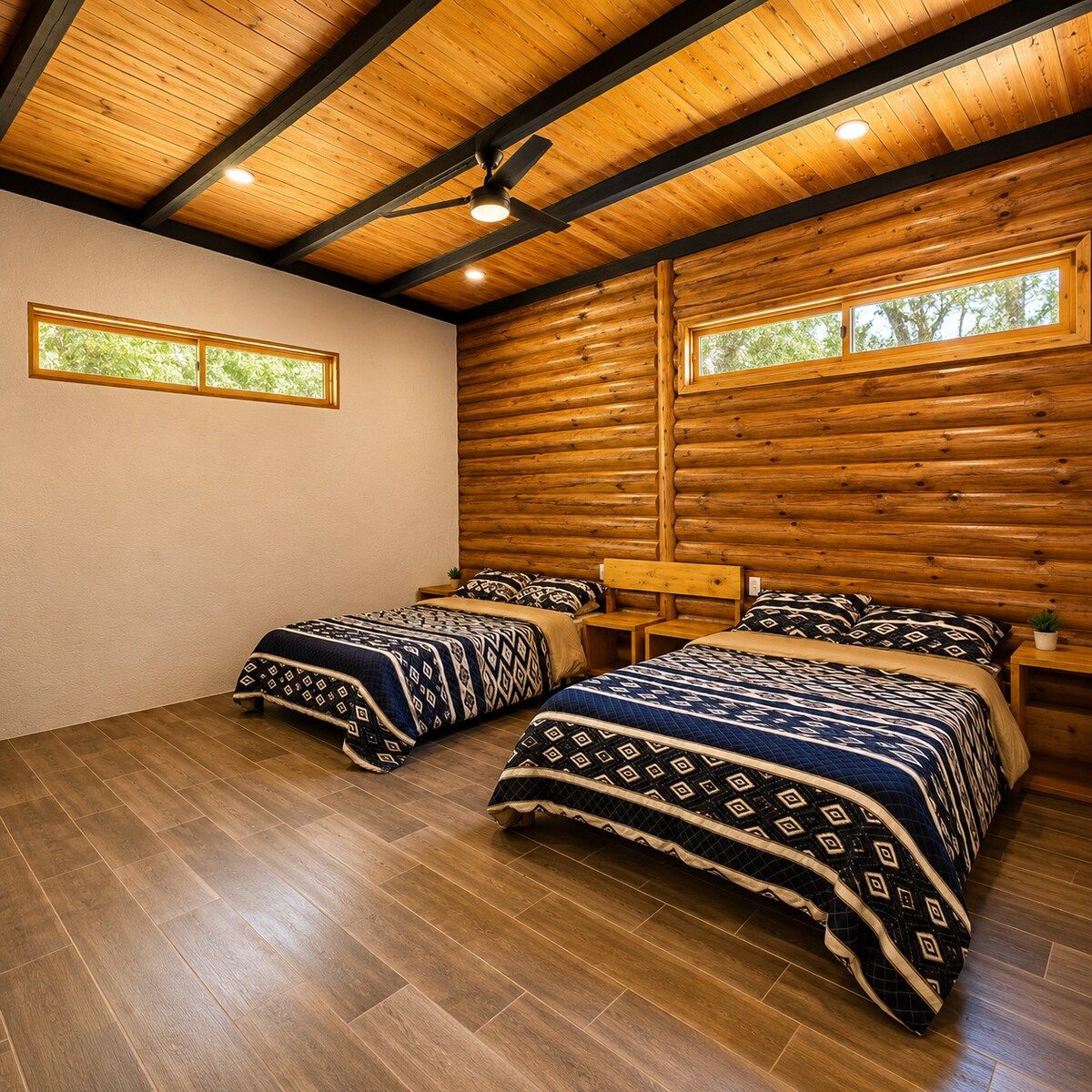 Ein Zimmer mit zwei Betten, Holzbalkendecke und einem Fenster mit Blick auf Bäume.