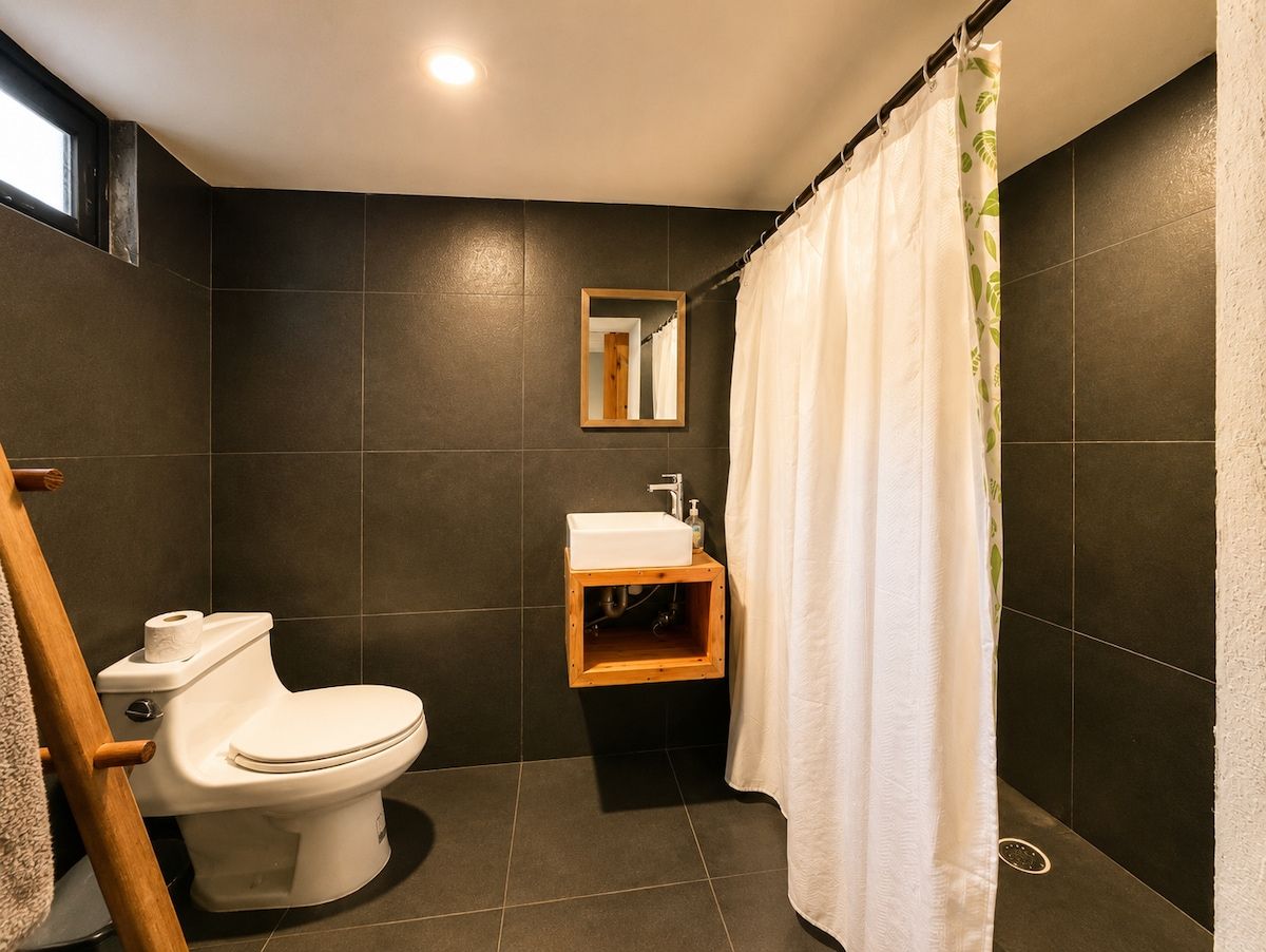 A modern bathroom with a toilet, sink, and shower curtain.