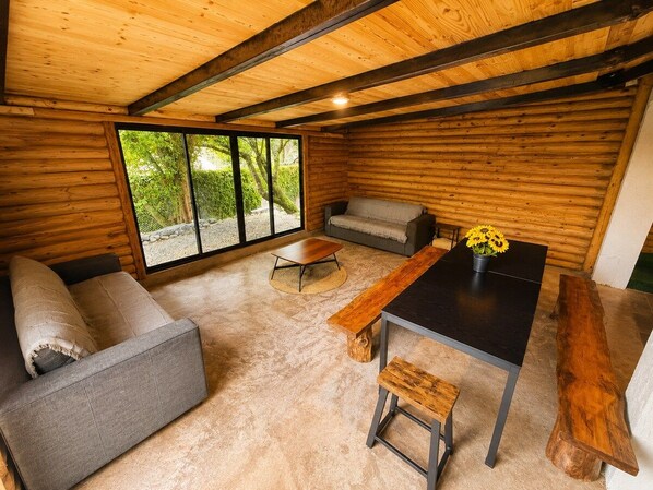 A log cabin interior with a sofa, a table, and a bench.