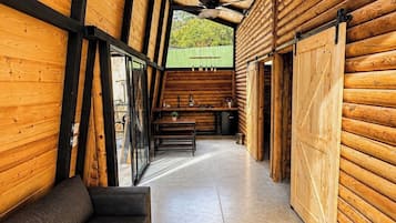 Un interior moderno con paredes de madera, techo negro, un sofá, una mesa de comedor y vistas a través de una ventana.