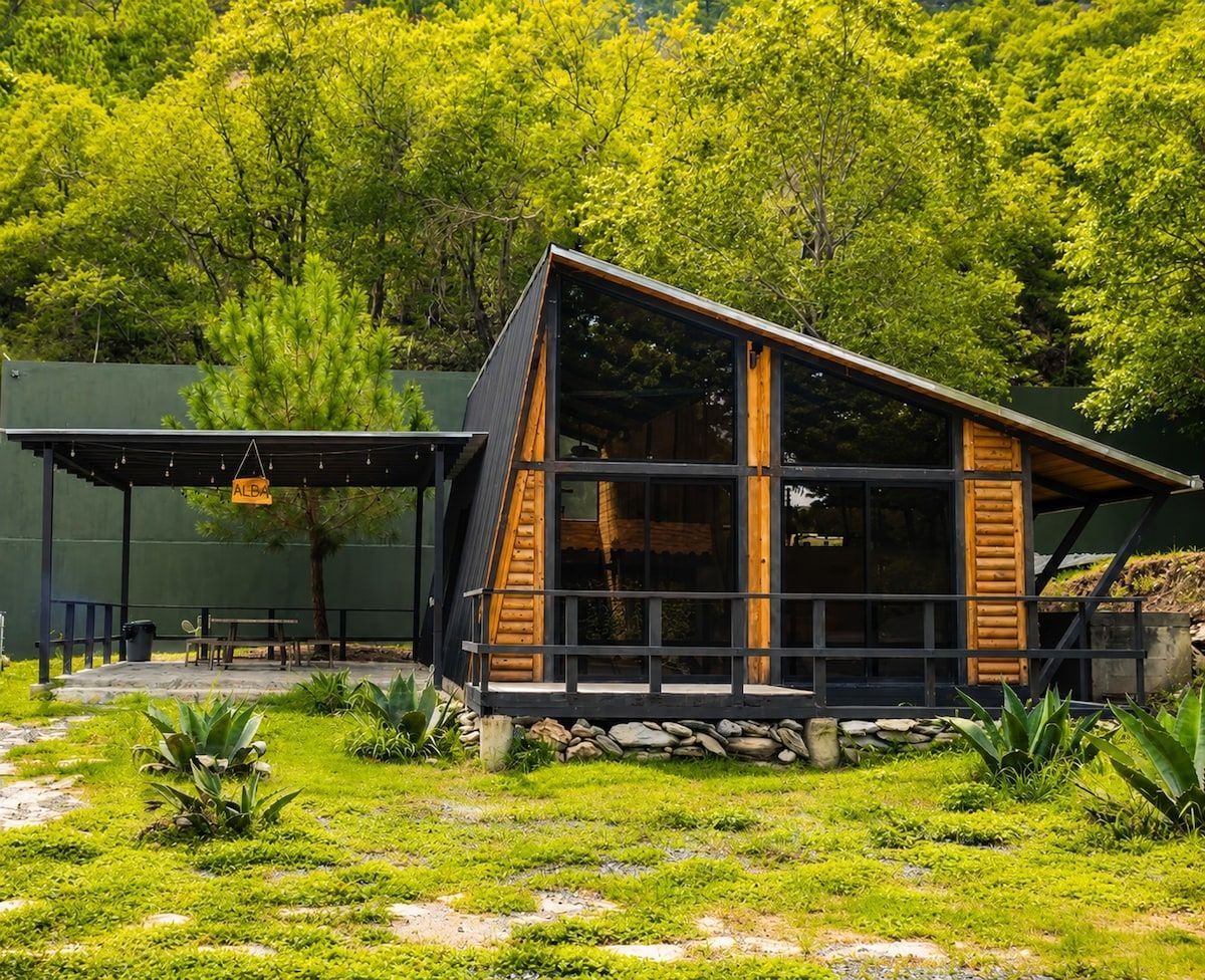 Eine moderne Hütte mit geneigtem Dach, großen Fenstern und einem Steinfundament.