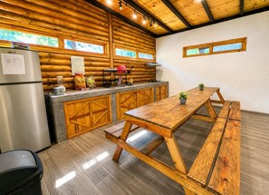 Une cuisine rustique avec des murs en bois, un réfrigérateur en acier inoxydable, une table en bois et un banc.