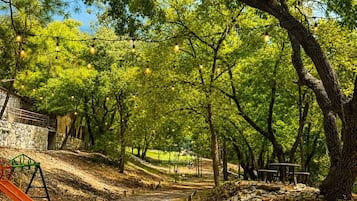 A park with a dirt path, trees, and a playground with a slide.