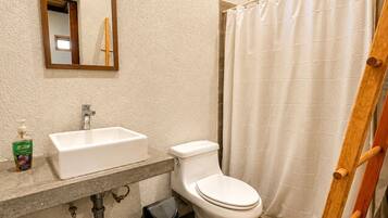 A bathroom with a white sink, toilet, and shower curtain.