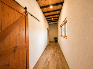 Un couloir avec une porte en bois, une fenêtre et une plante.