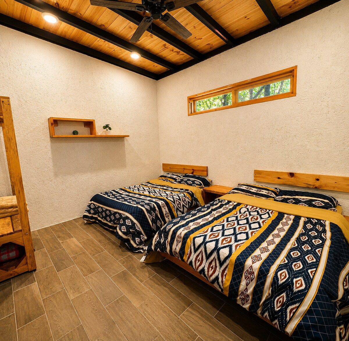 A room with two beds, wooden headboards, a shelf with a plant, and a window with a view of greenery.
