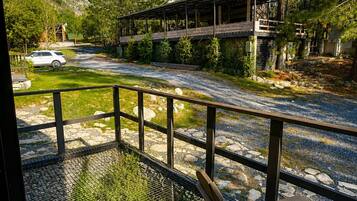 Una terraza de madera con un banco, un espacio al aire libre techado y vistas a la montaña.