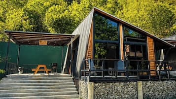 A modern building with a stone foundation, a wooden deck, and a metal roof.