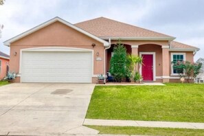 A residential house with a garage, a red door, and a well-maintained lawn. - Modern Gulfport Retreat. Stylish 1 BR, Full Kitchen, Patio & Private Driveway (Gulfport)