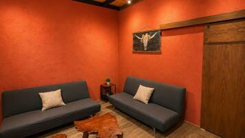 A room with two sofas, wooden coffee tables, and a wooden ceiling.