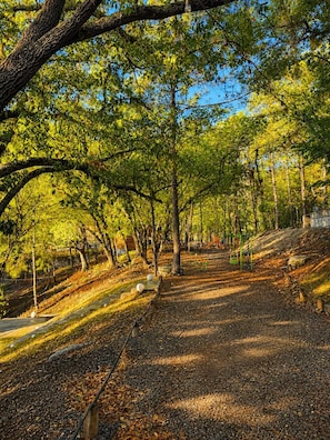 Un parque con un sendero pavimentado, árboles y juegos infantiles.