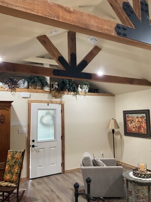 A room with a wooden ceiling, a white door, a grey armchair, a floor lamp, and a framed picture on the wall. - Welcome to Harrisons Haven on beautiful Lake Belton. Beautiful 1bd1bath cottage (Belton)