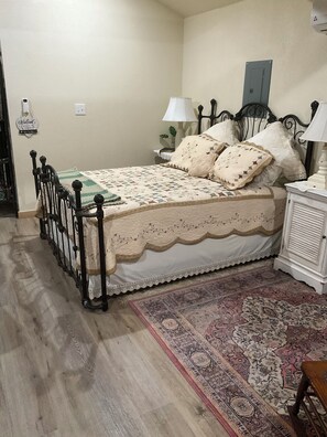 Une chambre à coucher comprenant un lit, des tables de chevet, une lampe, un tapis et un radiateur fixé au mur.