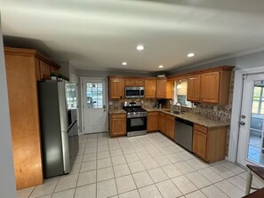 A kitchen with wooden cabinets, a stainless steel refrigerator, a microwave, an oven, and a dishwasher. - Spacious 4-Bedroom Retreat in peaceful Roswell (Roswell)