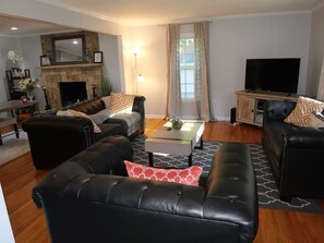 A living room with leather sofas, a fireplace, a television, and a coffee table. - Spacious 4-Bedroom Retreat in peaceful Roswell (Roswell)
