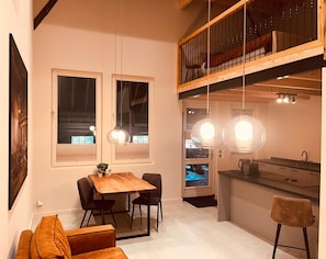 A modern kitchen with a wooden island, pendant lights, and a dining area with a wooden table and chairs.