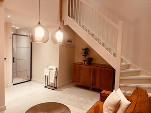 A modern interior with a staircase, a wooden cabinet, and a glass shower enclosure.