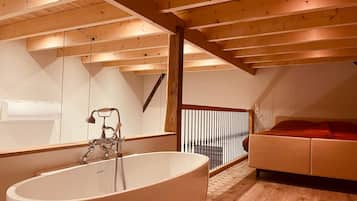 Ein modernes Badezimmer mit einer freistehenden Badewanne, einem großen Spiegel und einer Holzbeschichtung an der Decke.