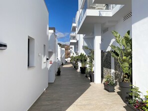 A narrow, sunlit corridor with white walls, potted plants, and a clear blue sky. - Apartment in Nerja With Panoramic Sea Views (Nerja)