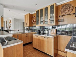 A modern kitchen with wooden cabinets, stainless steel appliances, and a black countertop. - Passy - Pdt. Kennedy 2 bd by B'Your Home (Paris)