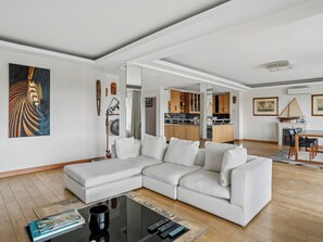 A modern living room with a sectional sofa, a coffee table, and a dining area with chairs. - Passy - Pdt. Kennedy 2 bd by B'Your Home (Paris)